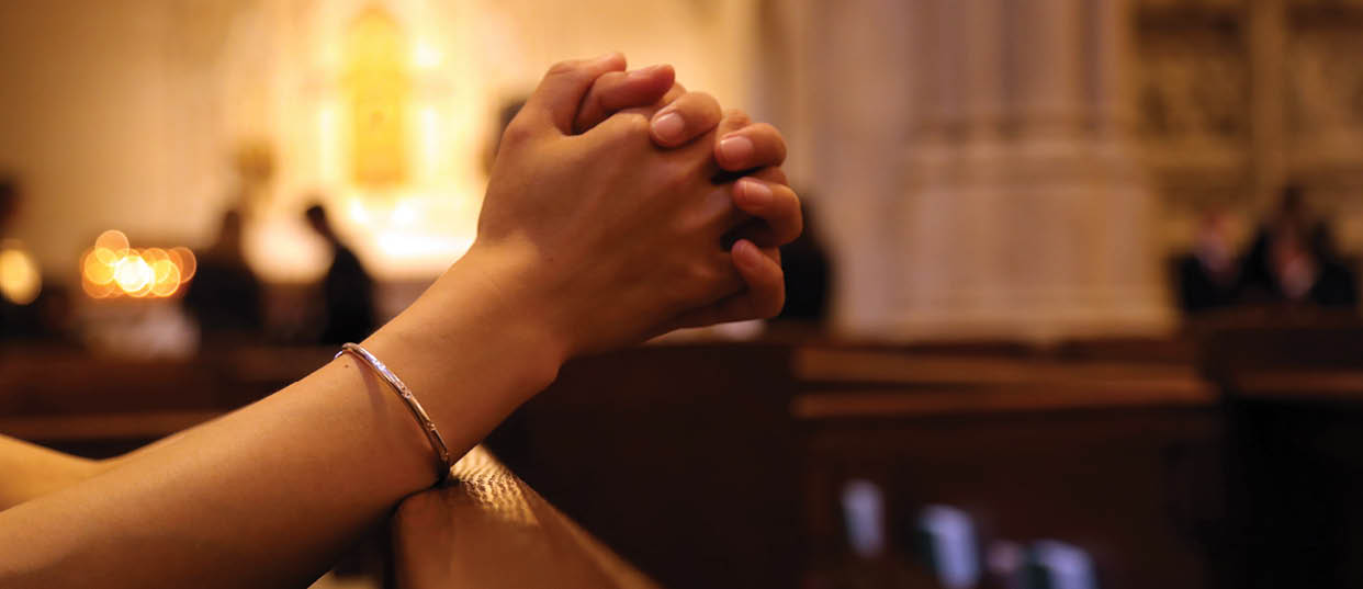 Closeup of woman's hands praying on church bench, coronavirus, copy space