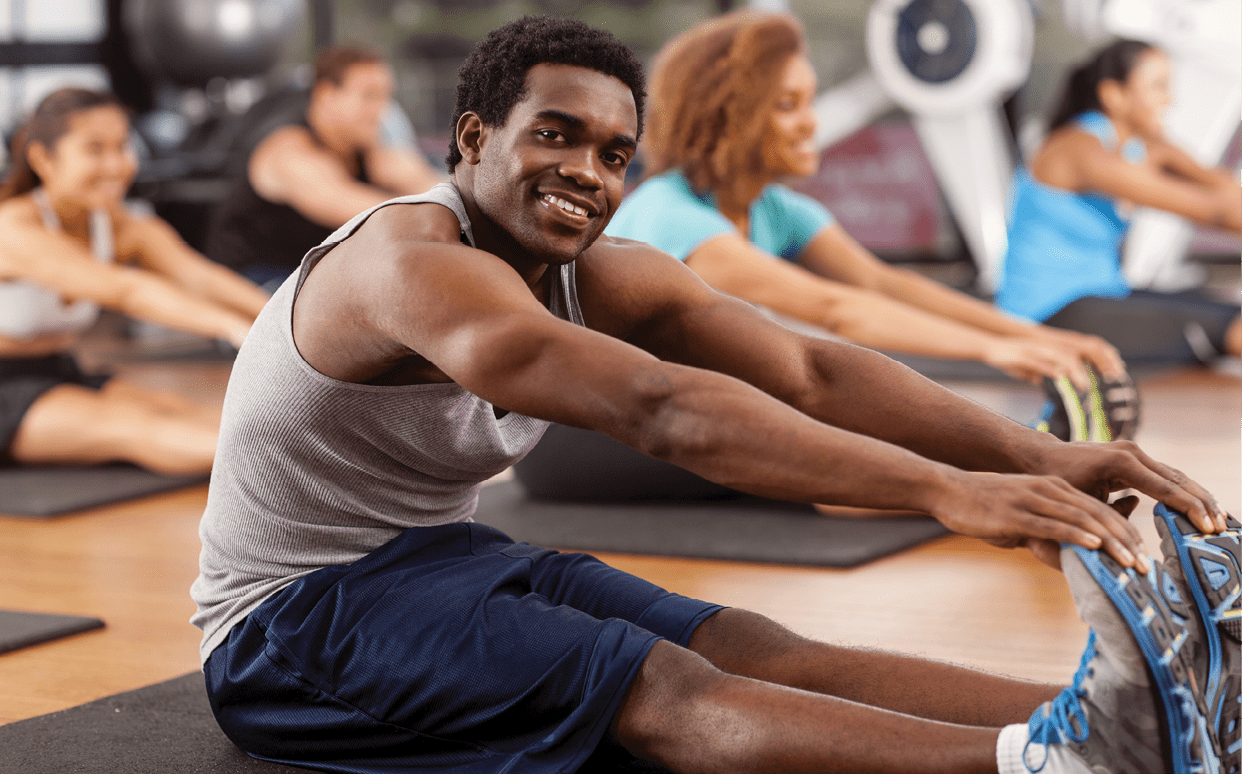 Young African-American man stretching in a gym and looking to camera