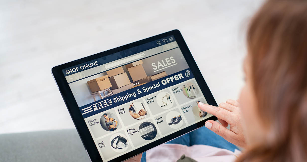 Back view of mature woman doing shopping online on website with digital tablet at home  Top view of woman with red hair relaxing on sofa while shopping online on ecommerce website  Rear view of girl hand touching screen while selecting product on e-commerce portal 