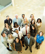 Multi-ethnic and mixed ages group of business people standing in office lobby area of building. They are looking up at camera. High-angle view.