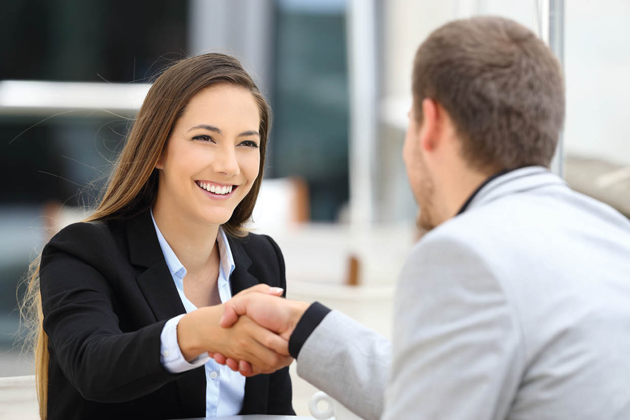 Two executives meeting and handshaking sitting in a coffee shop