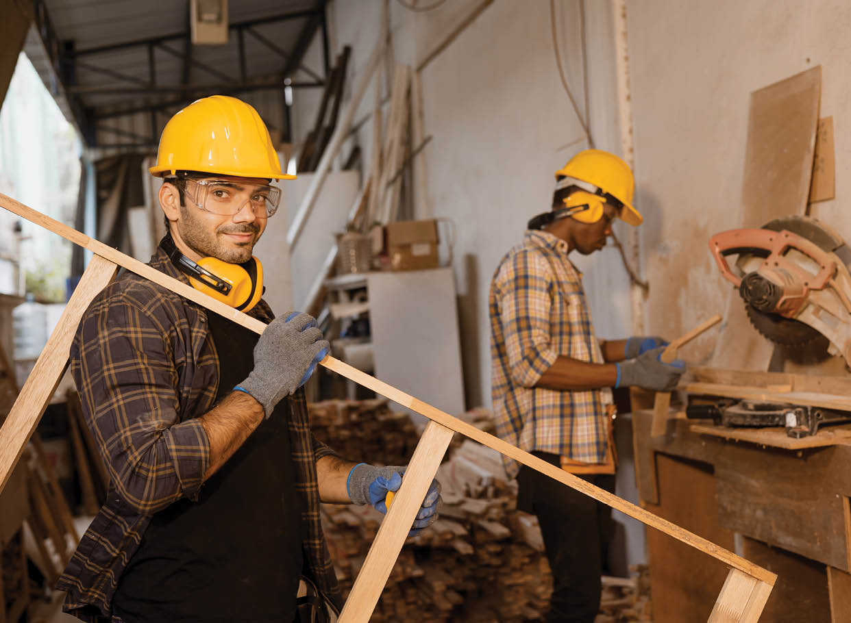 Happy worker working together in wood furniture factory, staff employee male making wooden wardrobe.