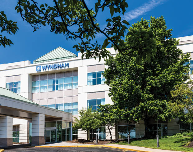 Exterior image of the entrance to the Wyndham Hamilton Park Hotel in summer