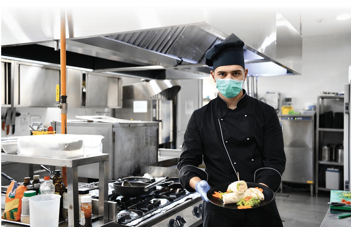 chef cook wearing face protective medical mask for protection from corona virus disease with plate of authentic sandwich at professional restaurant kitchen  Health, safety and pandemic concept in new normal concept