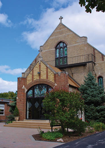 A church with a large brick building and a cross on top. Description generated by AI