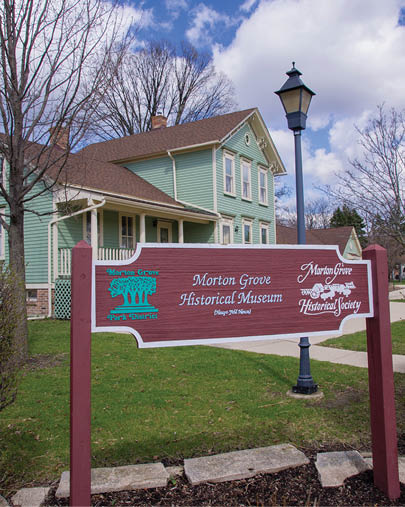 A sign on a red pole in front of a green house. Description generated by AI