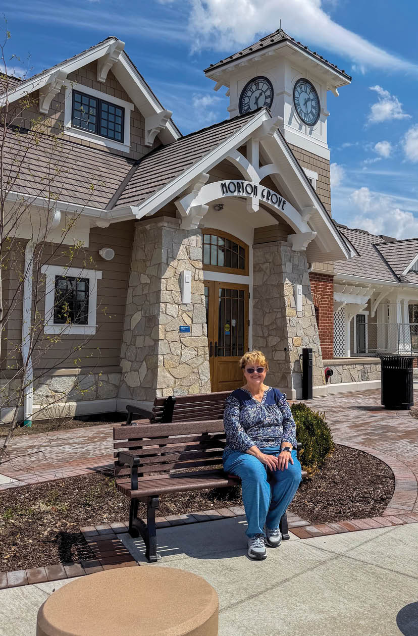 A woman sitting on a bench in front of a building. Description generated by AI