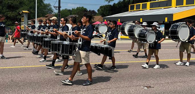 A group of people playing drums on a street. Description generated by AI