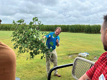 A man is holding a tree branch in a field. AI generated content