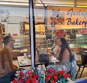 Three people are sitting at a table in a bakery, enjoying their food. AI generated content