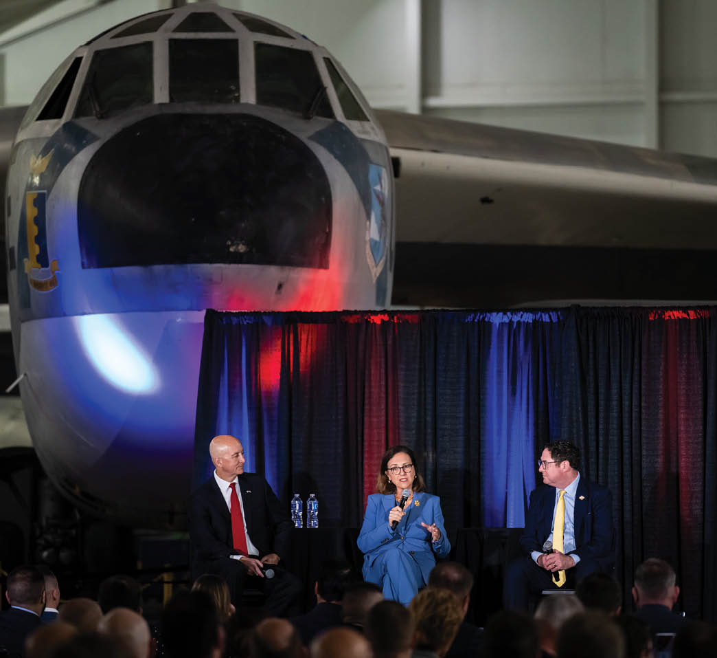 Three people are sitting on a stage in front of a large airplane. AI generated content