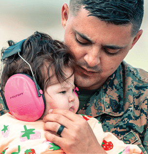A man wearing a camouflage shirt holding a baby. Description generated by AI
