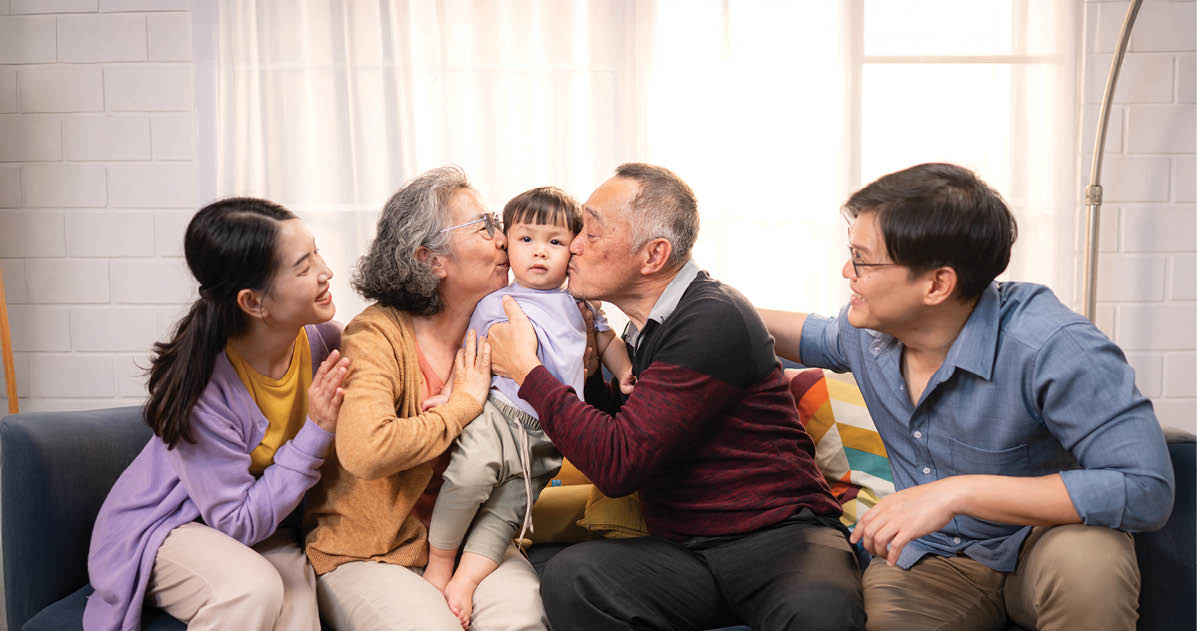 Happy multi-generational Asian family enjoying quality time together at home, cheering and smiling with a toddler
