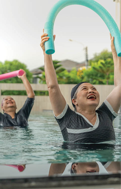 An engaging aquatic exercise class for seniors led by an instructor in a pool. The participants use colorful foam noodles, practicing water-based exercises to stay fit, healthy, and active.