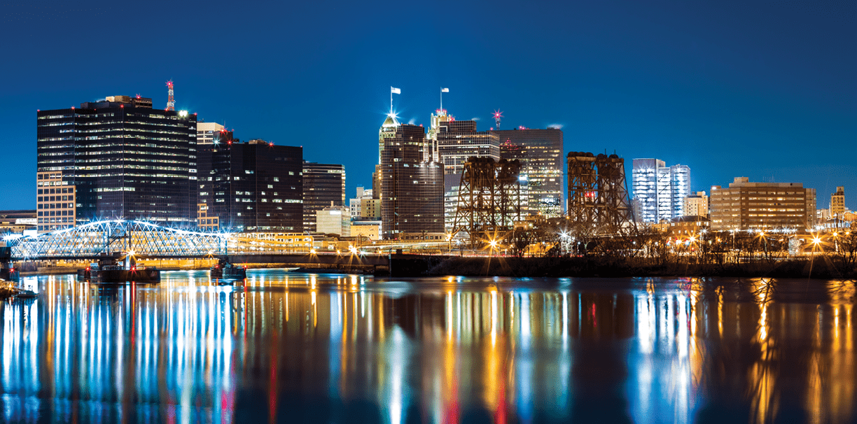 Newark, NJ cityscape by night, viewed from Riverbank park. Jackson street bridge, illuminated, spans the Passaic River