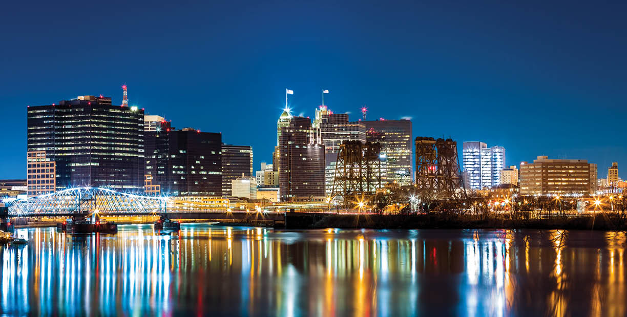 Newark, NJ cityscape by night, viewed from Riverbank park. Jackson street bridge, illuminated, spans the Passaic River
