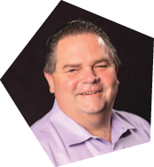 A man wearing a purple shirt and a tie is smiling for the camera. AI generated content