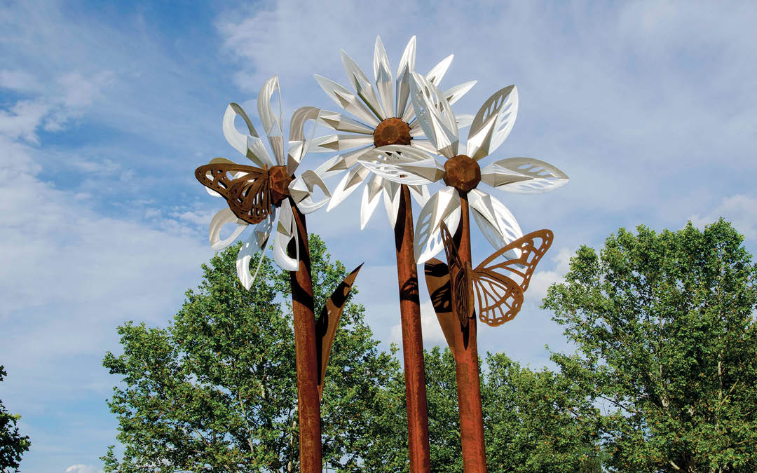 Two metal sculptures of flowers and butterflies are displayed in a park. AI generated content