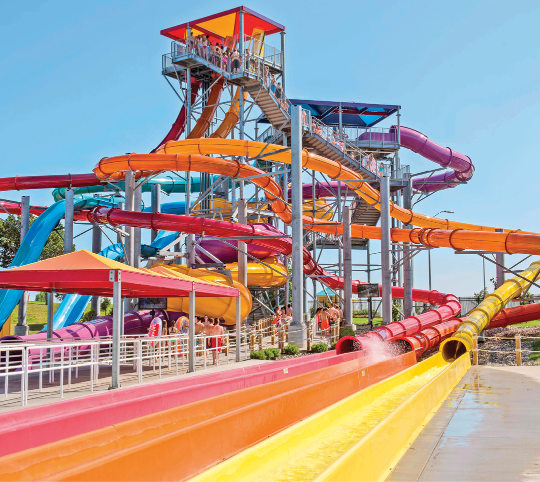 A water slide with a yellow and red tube is in a water park. AI generated content