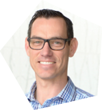 A man wearing glasses and a blue plaid shirt is smiling for the camera. AI generated content