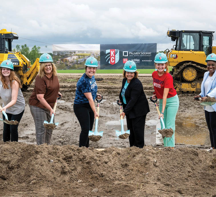 A group of women wearing hard hats are digging in a dirt field. AI generated content