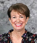 A woman wearing a floral print shirt and earrings is smiling for the camera. AI generated content