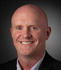 A bald man wearing a suit and tie is smiling for the camera. AI generated content