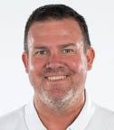 A man with a white shirt and white collar is smiling for the camera. AI generated content