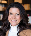 A woman in a brown jacket and white sweater is smiling for the camera. AI generated content