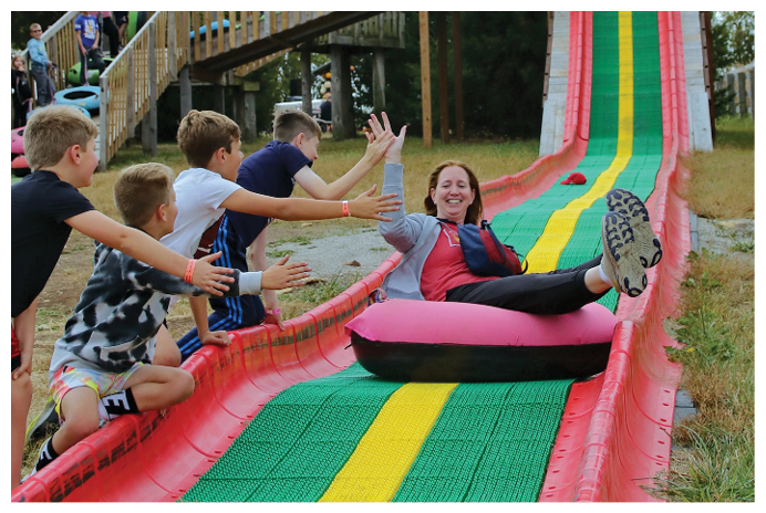 A woman is laying on a pink inflatable raft while a group of children hold her hands. AI generated content