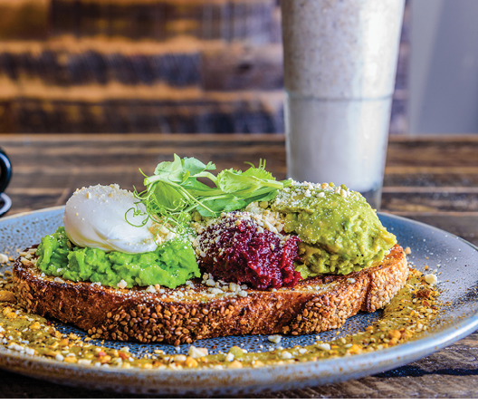 A plate of smashed avocado on toast with a poached egg on top