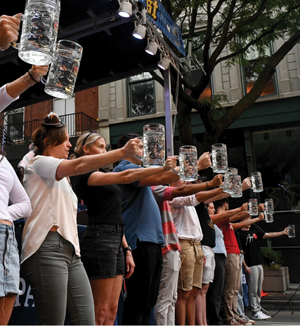 A group of people holding up beer mugs. Description generated by AI