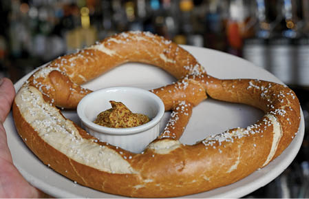 A plate with a pretzel on it and a small bowl of mustard. Description generated by AI