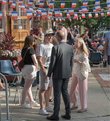 A group of people standing on a sidewalk. Description generated by AI