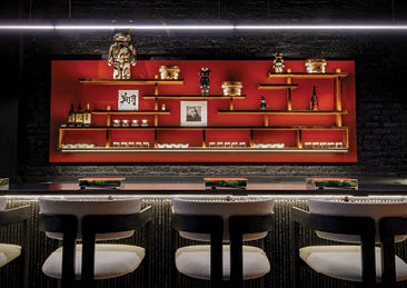 A bar with a red wall and a shelf with bottles and bowls. Description generated by AI