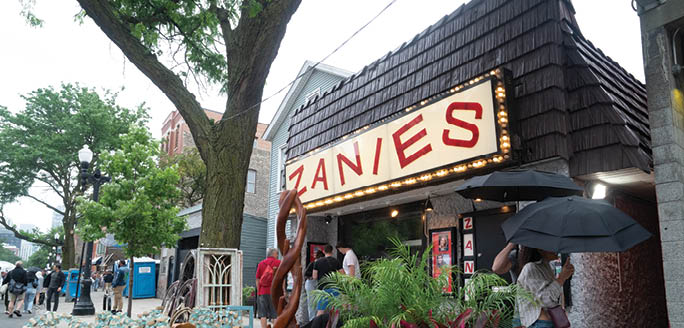A storefront with a neon sign that says Zanes. Description generated by AI