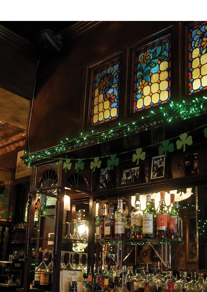 A bar with a shelf full of liquor bottles and a green and white decoration. Description generated by AI