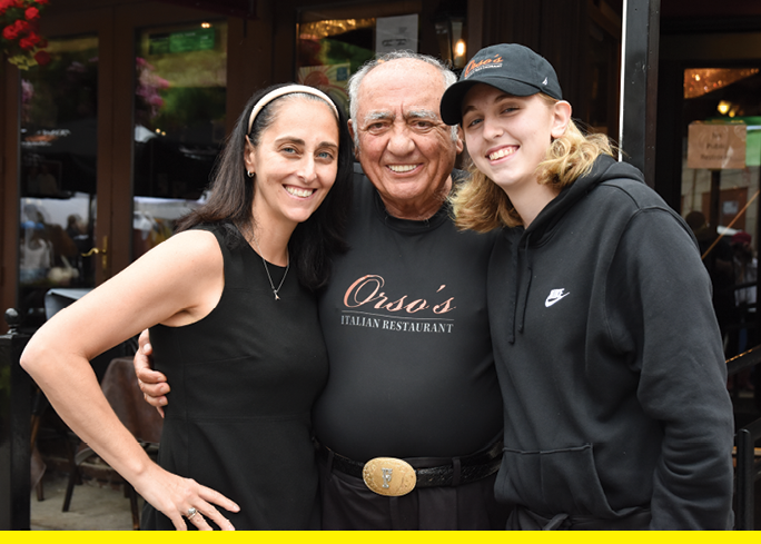 A man and two women are standing outside of a restaurant. Description generated by AI