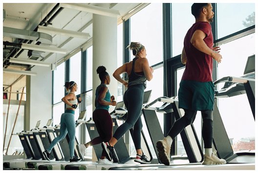 Back view of young athletes running on treadmill while having sports training in a gym.
