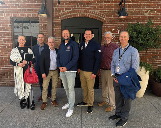 A group of people standing in front of a building. Description generated by AI