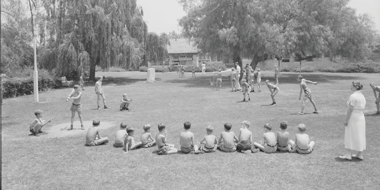 A group of boys sitting on the grass. Description generated by AI