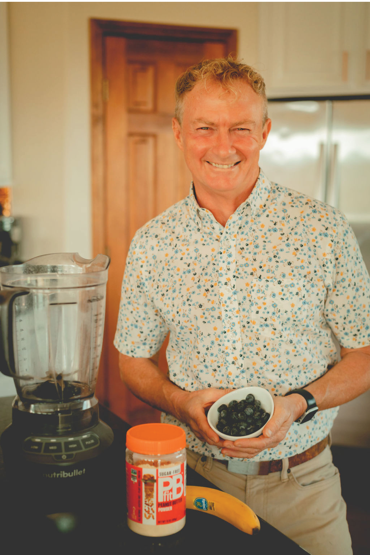 A man holding a bowl of blackberries. Description generated by AI