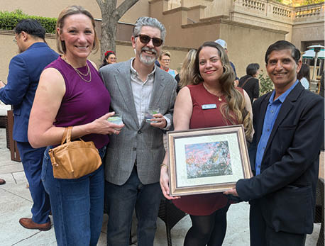 A group of people standing in front of a picture frame. Description generated by AI