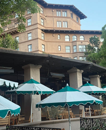 A row of green and white umbrellas are outside a building. Description generated by AI