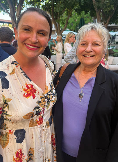 A woman wearing a floral shirt smiles for the camera. Description generated by AI