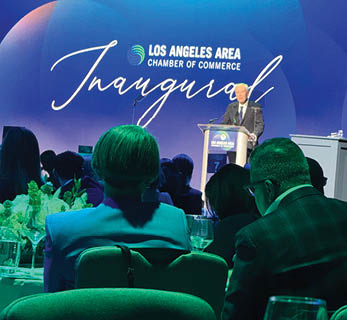 A man is speaking at a podium in front of a blue and white backdrop. Description generated by AI