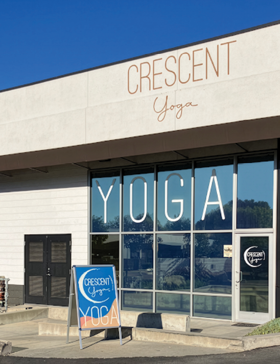 A yoga studio with a blue sign in front. Description generated by AI