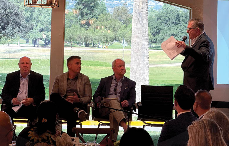 A group of men are sitting around a table, engaged in a discussion. One man is speaking, while the others listen. The men are wearing suits and ties, indicating a formal or professional setting. The scene takes place in a room with a large window, providing natural light. AI generated content