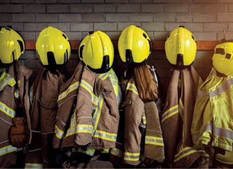 Firefighting gear including helmets, gloves, protection jacket and trousers among other clothing and equipment in fire station.