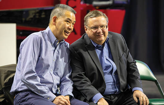 Two men are sitting on chairs, smiling and enjoying each other's company. AI generated content